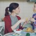 Joyful mother and cheerful daughter have fun grimacing silly with vegetables while cooking in the kitchen at home. Family, cook, and people concept